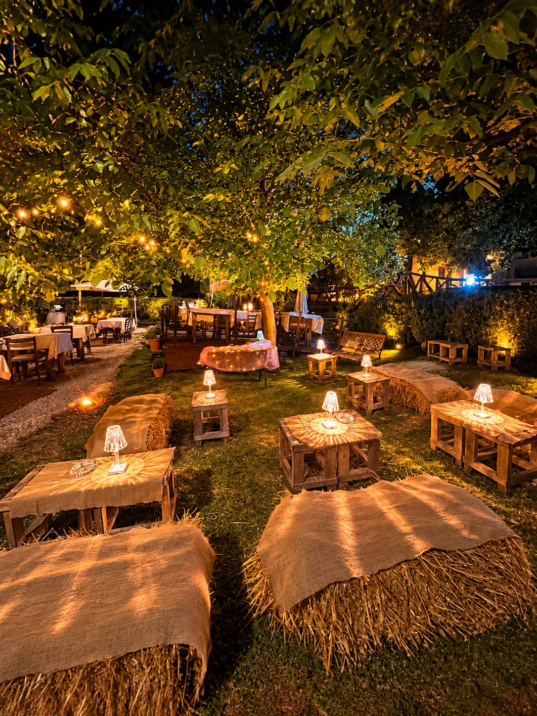 Il giardino di sera con lanterne e balle di fieno